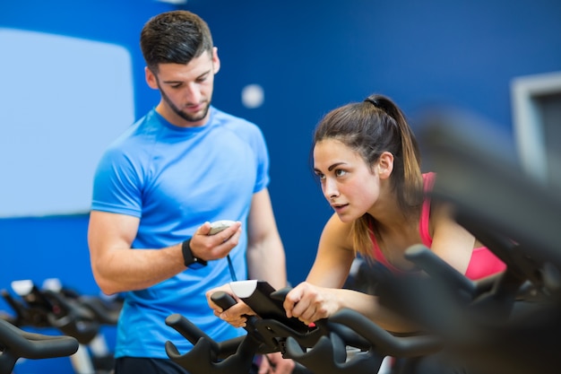 Woman on exercise bike with trainer timing her