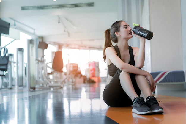 여자 운동 체육관에서 운동 피트니스 휴식 휴식 운동 후 단백질 이크 병을 마시는 스포츠 건강한 생활 방식 보디빌딩