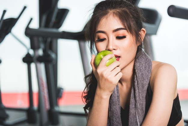 Женщина тренируется в тренажерном зале с зеленым яблоком после тренировки