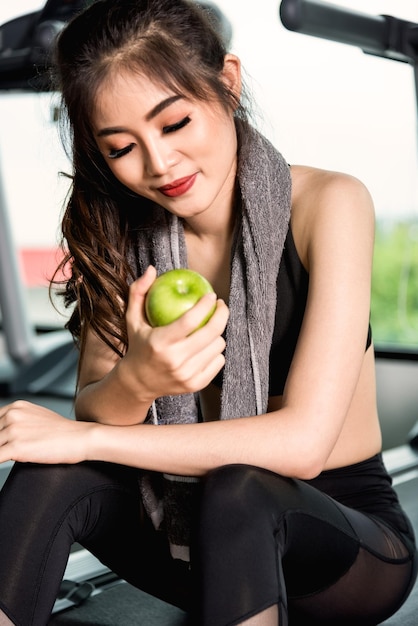 Woman exercise workout in gym fitness holding green apple fruit after training sport