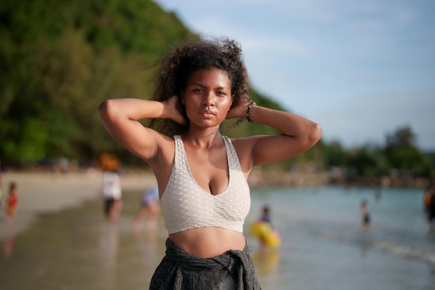 Woman exercises and stretches muscles before outdoor workout Portrait sexy Asian African lady preparing herself for fitness at beach