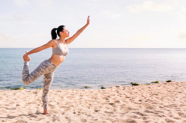 Woman exercising on the beach with yoga poses