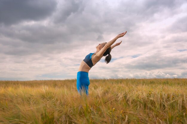 Woman exercising and doing a stretch in the middle of a field workout outdoors