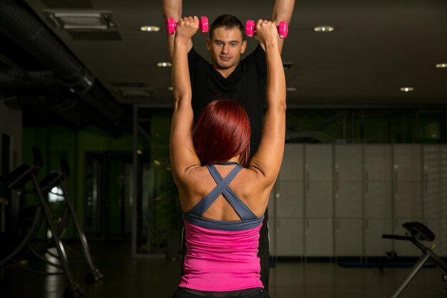 Foto donna che si esercita in palestra con personal trainer