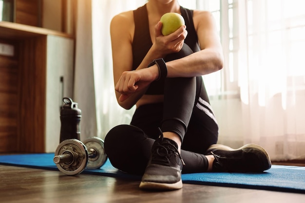 Woman exercising in the gym Young woman workout in fitness for her healthy She is holding green apple