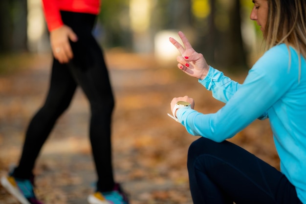 Foto donna che si esercita in un parco pubblico con un personal trainer in autunno con l'allenatore che conta i salti