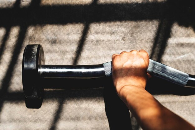 Woman exercising weighlifting with barbell at fitness gym