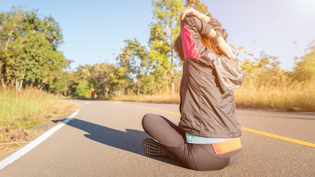 Photo woman exercising while sitting on road against sky