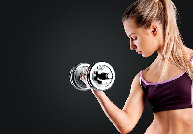 Woman exercising with dumbbell on background