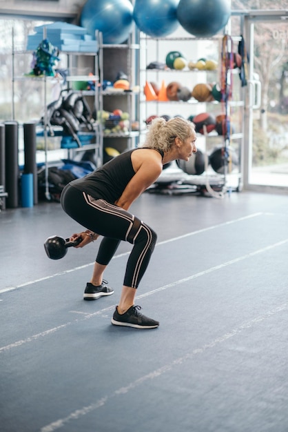 Photo woman exercising with kettlebell at gym