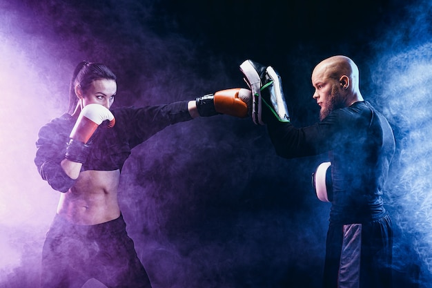 Donna che si esercita con l'istruttore alla lezione di boxe e dell'autodifesa