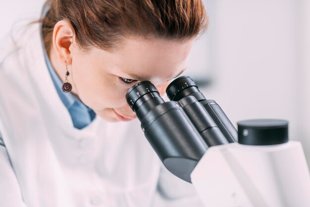 Foto donna che fa esperimenti con il microscopio in laboratorio