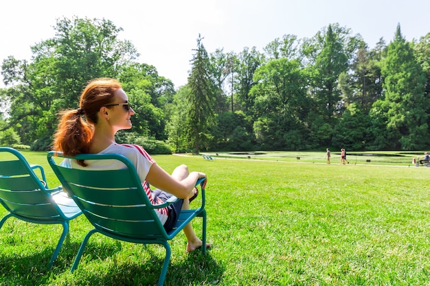 Woman in eyeglasses relax on greenfield.