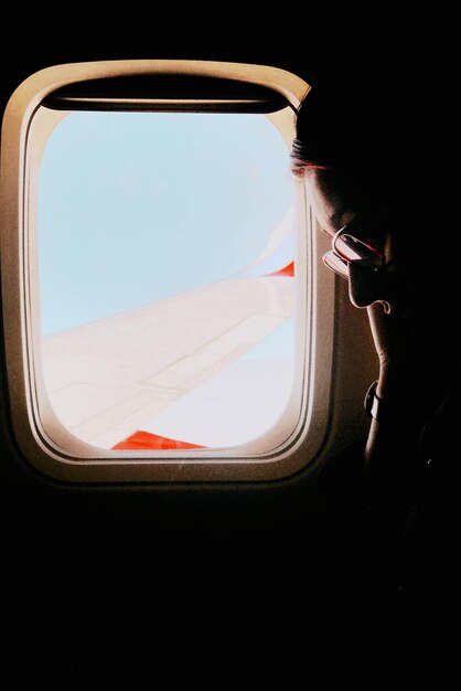 Photo woman in eyeglasses sitting by window in airplane