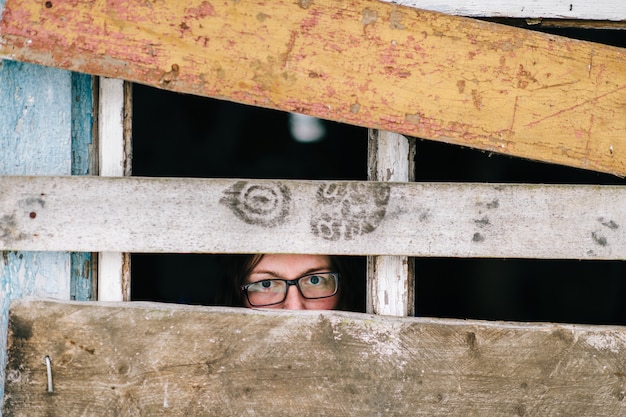 Woman face looking through the old wooden window