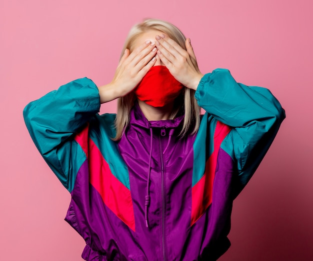 Woman in face mask and 80s clothes on pink