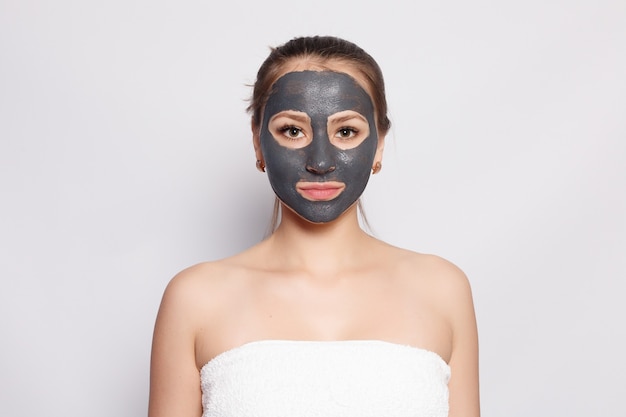 Maschera per il viso della donna. ritratto di bella ragazza che rimuove la maschera peeling nera cosmetica dalla pelle del viso. primo piano di giovane donna attraente con trucco naturale e maschera di buccia cosmetica sul viso. alta risoluzione