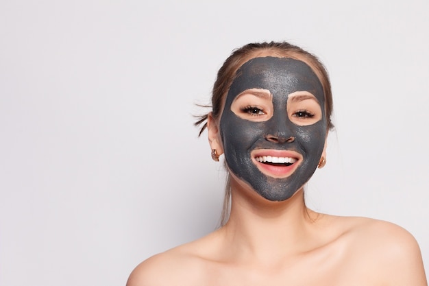 Maschera per il viso della donna. ritratto di bella ragazza che rimuove la maschera peeling nera cosmetica dalla pelle del viso. primo piano di giovane donna attraente con trucco naturale e maschera di buccia cosmetica sul viso. alta risoluzione