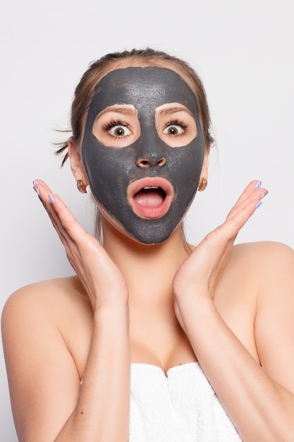 Foto maschera per il viso della donna. ritratto di bella ragazza che rimuove la maschera peeling nera cosmetica dalla pelle del viso. primo piano di giovane donna attraente con trucco naturale e maschera di buccia cosmetica sul viso. alta risoluzione