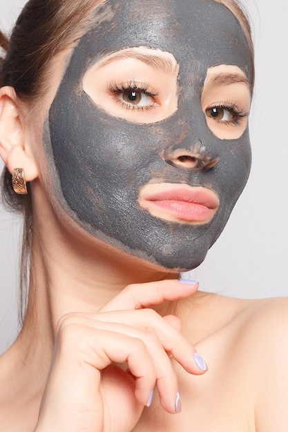 Photo woman face mask. portrait of beautiful girl removing cosmetic black peeling mask from facial skin. closeup of attractive young woman with natural makeup and cosmetic peel mask on face. high resolution