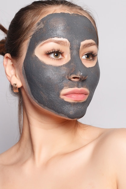 Woman Face Mask. Portrait Of Beautiful Girl Removing Cosmetic Black Peeling Mask From Facial Skin. Closeup Of Attractive Young Woman With Natural Makeup And Cosmetic Peel Mask On Face. High Resolution