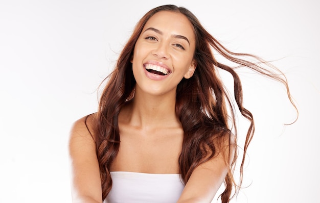 Woman face skincare and windy hair on white background in studio for keratin treatment healthcare wellness or color dye marketing Portrait smile or happy beauty model with brunette waves or style