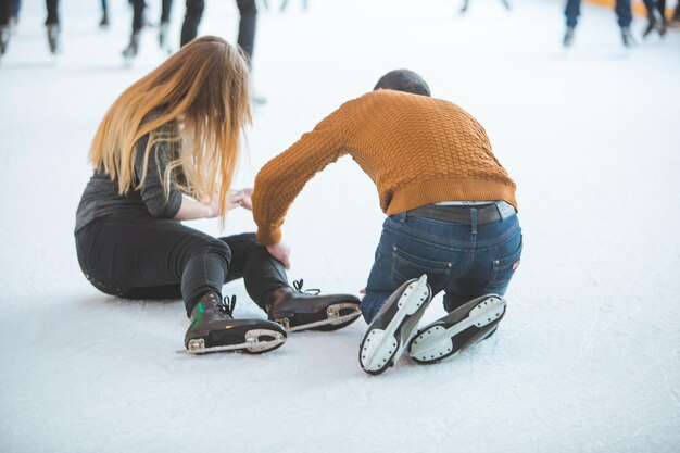 woman fall down while skating man helping her