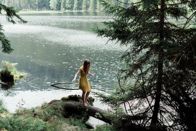 Woman on fallen tree by lake