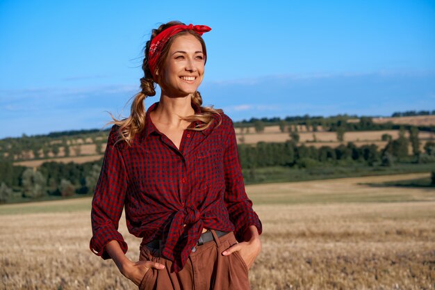 Foto agricoltore donna in piedi terreno agricolo sorridente