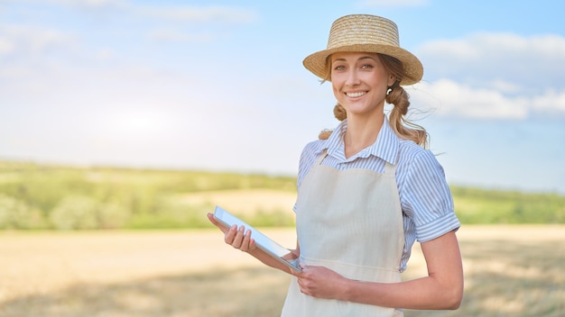 Woman farmer straw hat smart farming standing farmland smiling using digital tablet Female agronomist specialist research monitoring analysis data agribusiness