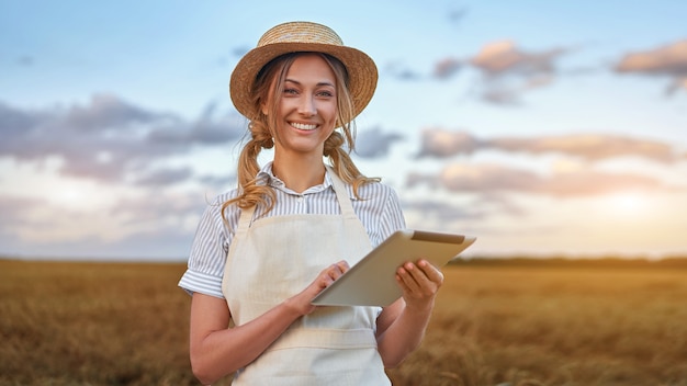 여성 농부 밀짚모자 스마트 농업 서 있는 농지 디지털 태블릿을 사용하여 웃는 여성 농업 경제학자 전문 연구 모니터링 분석 데이터 농업 기업