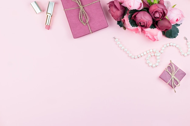 Woman fashion accessories, flowers, cosmetics and jewelry on pink background, copyspace.