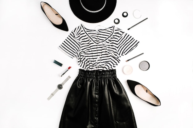 Foto flatlay moda donna. abiti e accessori moderni neri. gonna, maglietta, cappello, scarpe, rossetto, orologi, cipria su sfondo bianco. lay piatto