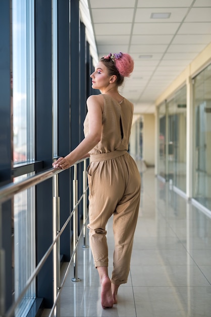 Woman in fashion pink dress and white shoes posing in corridor