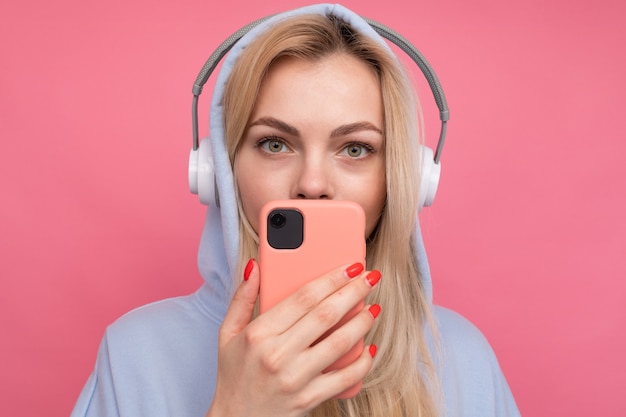 A woman in a fashionable hoodie listens to music from her phone