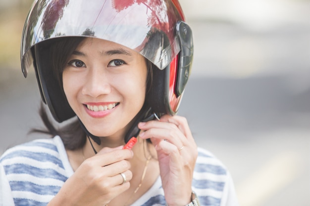 Donna che allaccia il suo casco da motociclista