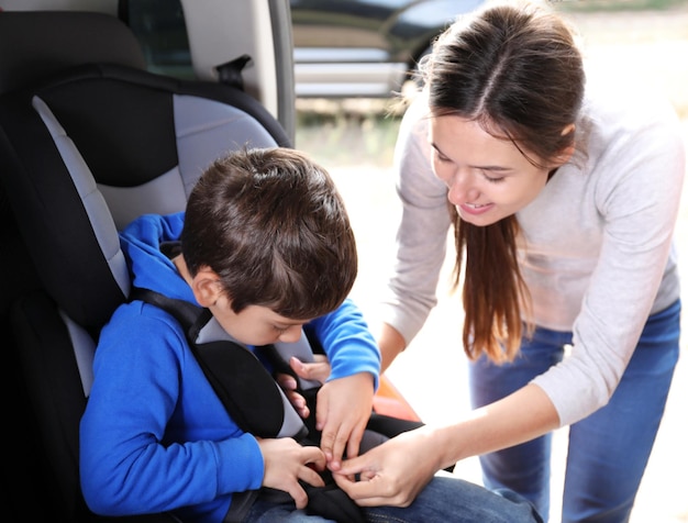 Foto donna che fissa suo figlio con la cintura di sicurezza dell'auto