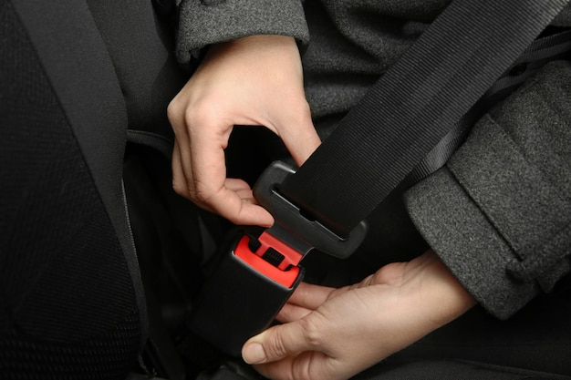 Woman fastening seat belt in car closeup