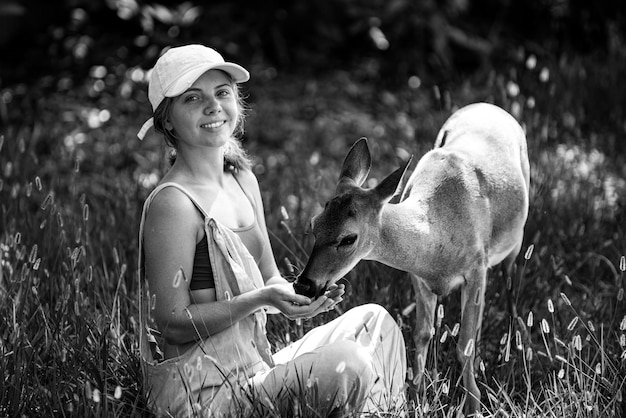 Woman feed deer wild animals concept woman feeding fawn animal at park