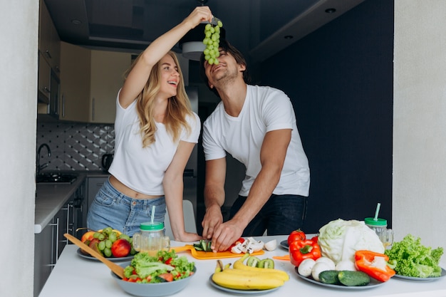 Woman feeding a man with grapes during man cutting a vegetable