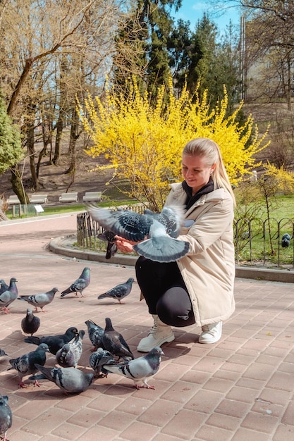 Женщина кормит голубей в общественном парке.