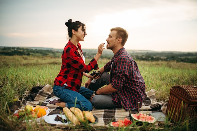 Woman feeds grapes to her man on picnic