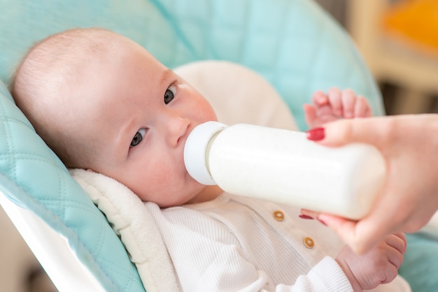 Woman feeds her baby milk from a bottle.