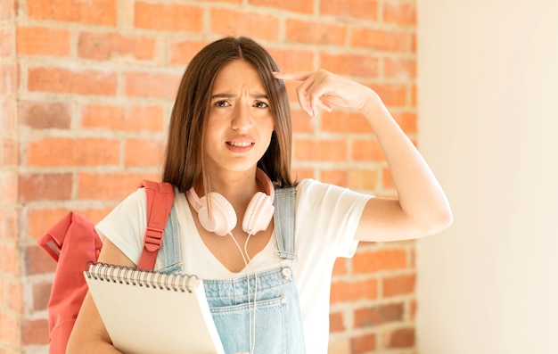 woman feeling confused and puzzled, showing you are insane, crazy or out of your mind