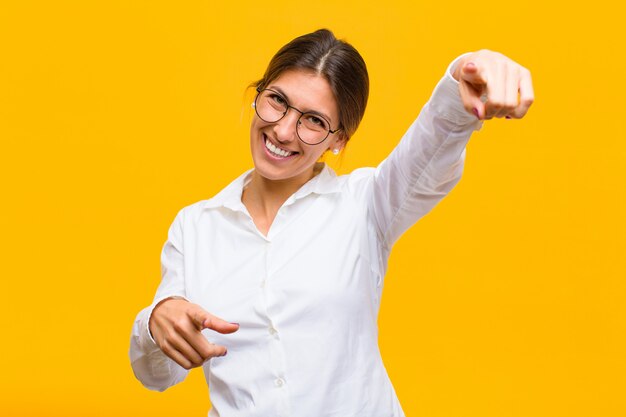 Woman feeling happy and confident, pointing with both hands and laughing, choosing you