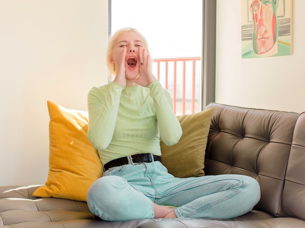 Woman feeling happy, excited and positive, giving a big shout out with hands next to mouth, calling out