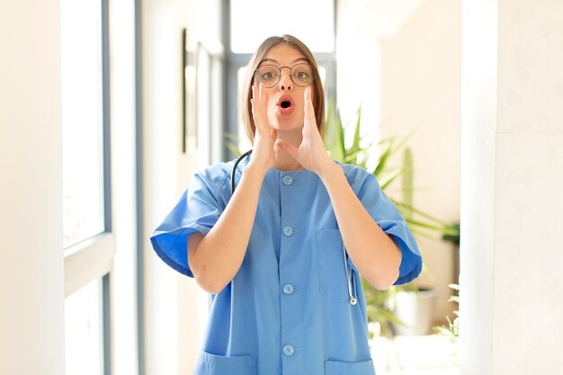 woman feeling happy, excited and positive, giving a big shout out with hands next to mouth, calling out