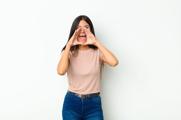 woman feeling happy, excited and positive, giving a big shout out with hands next to mouth, calling out