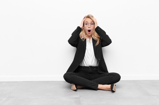 woman feeling horrified and shocked, raising hands to head and panicking at a mistake