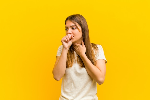 woman feeling ill with a sore throat and flu symptoms, coughing with mouth covered